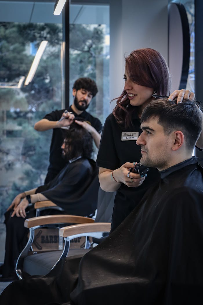 Barber and stylist working on clients in a contemporary salon environment, capturing the art of hairstyling.